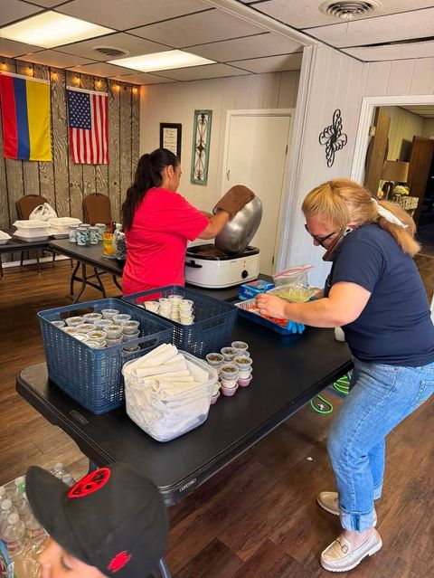 Church members preparing plates of food for a fundraiser, beneath the Colombian and American flags.